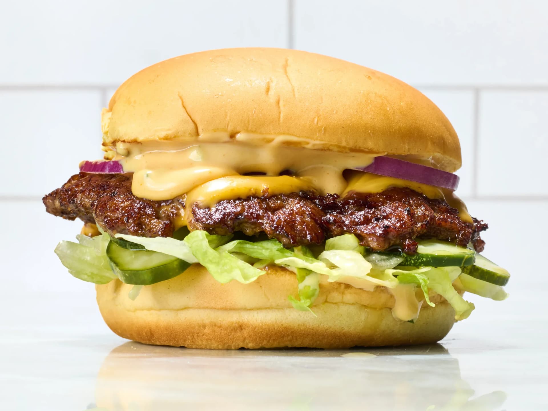 Homemade smash burger with crispy edges, melted old cheddar, and bacon on a brioche bun.